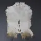 Natural goatskin rug with white and grey fur, featuring brown patches at the bottom edge.