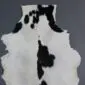 Natural goatskin rug with white fur and irregular black patches.