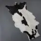 Natural goatskin rug with a black and white speckled pattern and irregular edges on a grey background.
