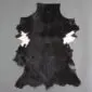 Natural goatskin rug with black fur and small white patches on the sides.