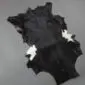 Natural goatskin rug with short black fur and small white patches on the edges.