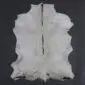 Natural goatskin rug with white and light grey fur, featuring an irregular shape and a dark central dorsal stripe.