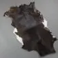 Goatskin Rug G1025 (1) Natural goatskin rug with dark brown and black fur featuring white patches on the edges.