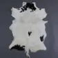 Natural goatskin rug with white fur and irregular black spots.