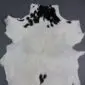 Natural goatskin rug with white fur and black spotted markings.