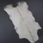 Natural white goatskin rug with a dark grey dorsal stripe and irregular edges.