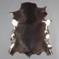 Natural goatskin rug with dark brown fur and white patches along the edges, shown from above on a grey background.