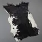 Natural goatskin rug with a black and white speckled pattern and irregular edges.