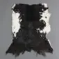 Natural goatskin rug with a large black centre and white speckled edges on a grey background.