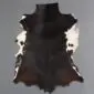 Natural goatskin rug with dark brown and black fur featuring white patches along the edges.
