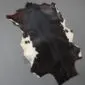 Natural goatskin rug with dark brown and black fur featuring white patches along the edges. detail view