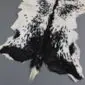 Natural goatskin rug with a speckled black and white pattern and irregular edges.