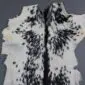 Natural goatskin rug with white fur and symmetrical black speckled markings.