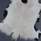 Natural goatskin rug with white fur and black patches along the edges.