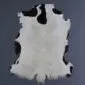 Natural goatskin rug with a white centre and black patches around the edges.