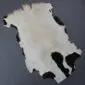 Natural goatskin rug with a large white centre and black patches around the irregular edges.