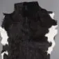 Natural goatskin rug with black fur and white patches along the irregular edges.
