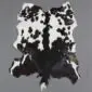 Natural goatskin rug with a speckled black and white pattern and irregular edges.