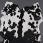 Natural goatskin rug with a black and white spotted pattern and irregular edges.