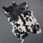 Natural goatskin rug with irregular black and white patches and a speckled pattern.