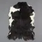 Natural goatskin rug with a black and white mottled pattern and irregular edges.