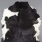 Natural goatskin rug with a mottled black and white pattern and irregular edges.