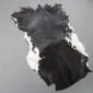 Natural goatskin rug with black and dark brown fur and white edges.