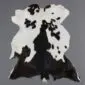 Natural goatskin rug with a black and white speckled pattern and an irregular organic shape.