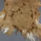 Natural goatskin rug with tan, brown and white mottled fur and irregular edges.