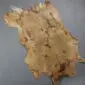 Natural goatskin rug with light brown and cream mottled fur in an irregular shape.