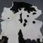 Natural goatskin rug with white fur and irregular black spots and patches.