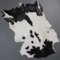 Natural goatskin rug with a speckled black and white pattern and irregular edges.