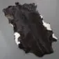 Goatskin Rug G1064 (4) Natural goatskin rug with an irregular shape featuring dark brown fur and white patches on the edges.
