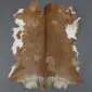Natural goatskin rug with tan and white patches and a dark brown dorsal stripe.