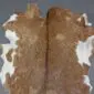 Natural goatskin rug with brown and white mottled patterns and a dark central dorsal stripe.
