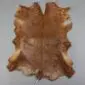 Natural goatskin rug with mottled brown and tan fur in an irregular hide shape.