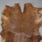 Natural goatskin rug with mottled brown and tan fur, featuring an irregular organic shape.