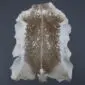 Natural goatskin rug with a brown speckled centre and cream outer edges on a dark grey background.