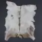 Natural goatskin rug with white and light brown fur, featuring a dark central stripe and irregular edges.