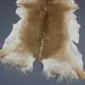 Natural goatskin rug with long, textured tan and cream fur and an irregular shape.