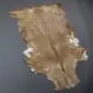 Natural goatskin rug with mottled brown and tan fur, featuring white patches along the edges.