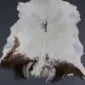 Natural goatskin rug featuring white fur with dark brown and black markings along the lower edges.
