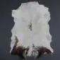 Natural goatskin rug with white fur and dark brown markings along the bottom edge.