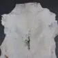 Natural white goatskin rug with grey and black markings and an irregular shape.
