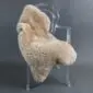 Beige sheepskin rug with thick, natural wool pile laid flat. detail view