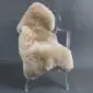 Beige sheepskin rug with thick, natural wool pile laid flat.