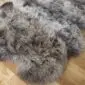Close-up of a triple rare breed sheepskin rug with long, textured grey and brown wool on a wooden floor.