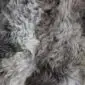 Close-up of a rare breed sheepskin rug featuring long, wavy wool in mottled shades of grey, cream, and brown.
