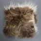 Square Icelandic sheepskin cushion with long, shaggy wool in spotted rusty brown and cream tones.