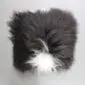 Square Icelandic sheepskin cushion with long, shaggy black wool and a distinct white patch at the base.